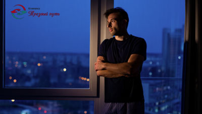 Мужчина ночью стоит у окна